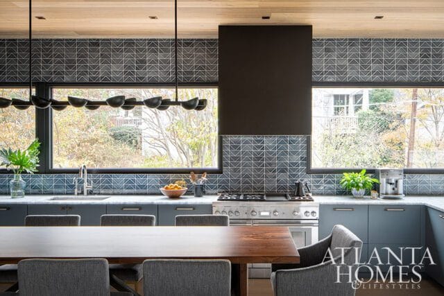 Modern kitchen with blue cabinets, geometric tile backsplash, and stainless steel appliances.