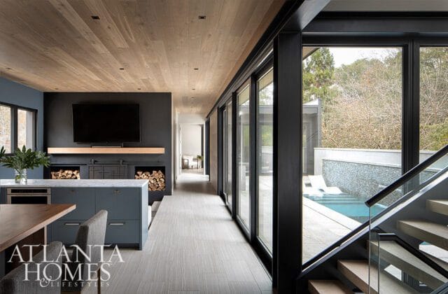 Modern living room with wood ceiling, dark gray walls, fireplace, and island.
