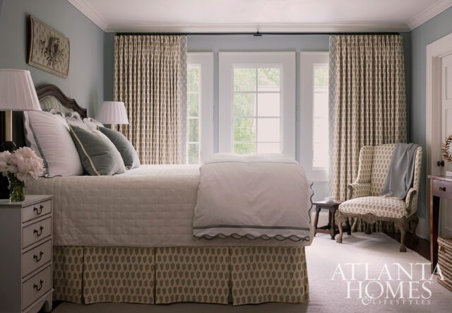 Bedroom with a queen bed, patterned curtains, and upholstered armchair.