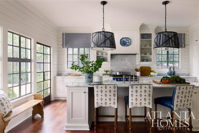White kitchen with marble island, blue patterned bar stools, and black grid windows.