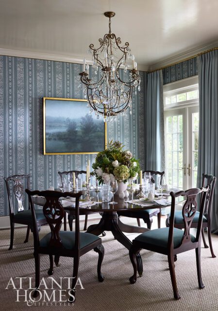 Dining room with blue striped wallpaper, crystal chandelier, and a table set for dinner.
