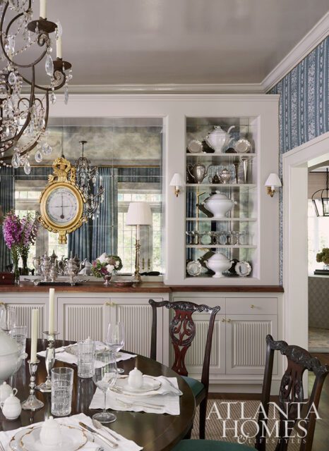 Dining room with a table set for a meal, built-in shelves with china, and a large clock on a