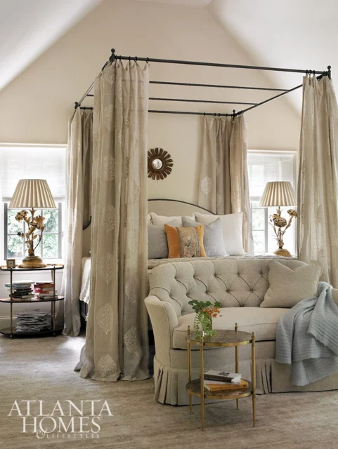 Bedroom with canopy bed, tufted sofa, and decorative lamps.