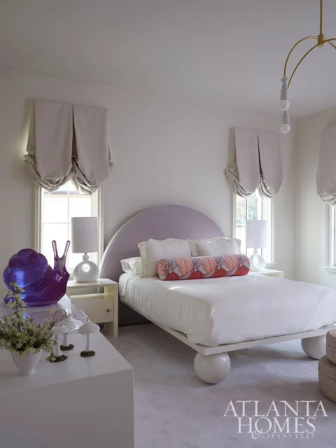 Girls bedroom with purple arched headboard, white bedding, and purple snail sculpture.