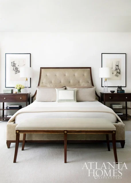 Bedroom with tufted headboard, neutral bedding, and dark wood nightstands with lamps.