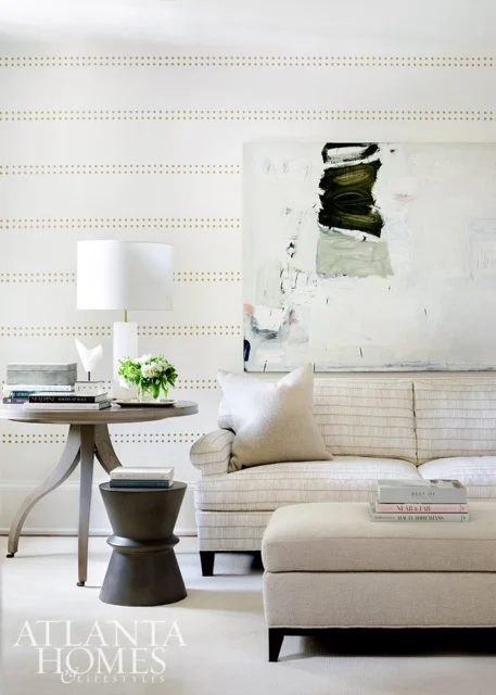Living room with striped sofa, abstract art, and round side table with lamp