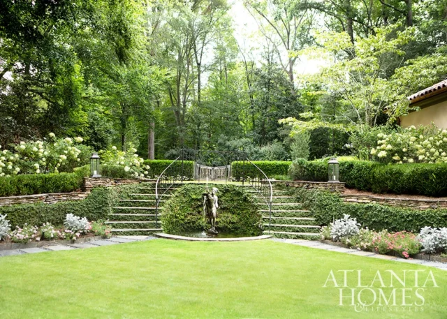 Terraced garden with stone steps, fountain statue, and lush greenery.