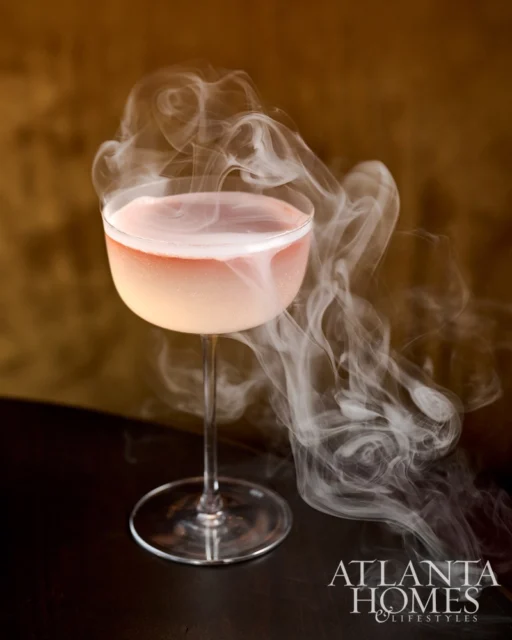 Pink cocktail in coupe glass with smoke swirling around it.