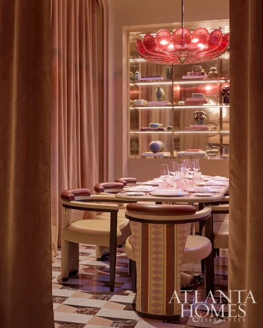 Dining room with plush pink curtains, a table set for dinner, and a red lotus-shaped chandelier.