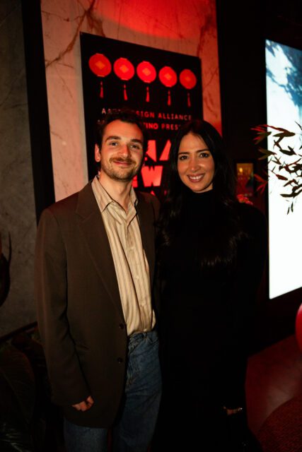 Man in brown suit jacket and striped shirt, woman in black turtleneck