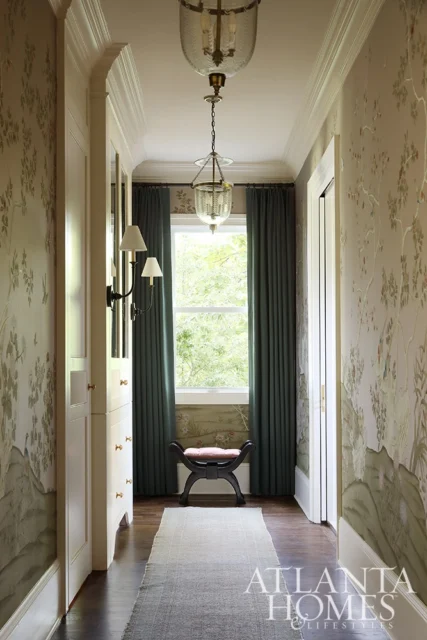 Hallway with floral wallpaper, dark teal curtains, and two pendant lights.