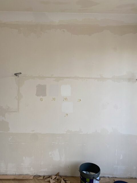 Wall with paint swatches, electrical wires, and a bucket of paint