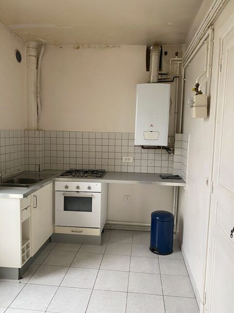 White kitchen with white tiled backsplash, white oven and stovetop, and stainless steel countertop.