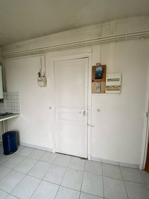White door with paneling, gas meter, and electrical panel on white walls.