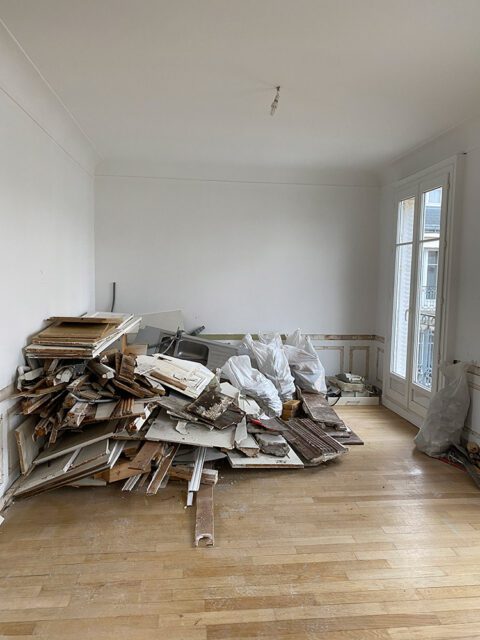 Room with pile of construction debris, white walls, wood floor, and French doors.