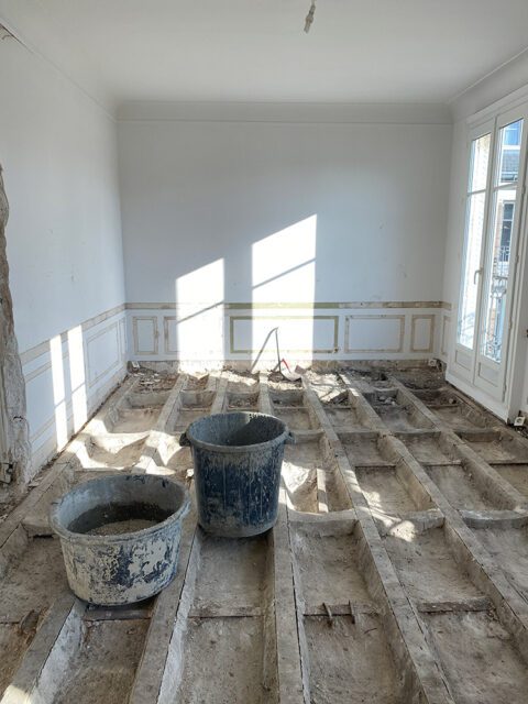 Room under renovation with exposed floor joists and two buckets on the floor.