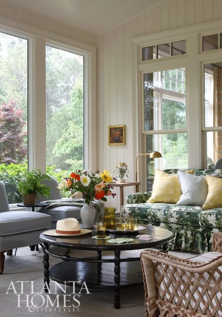 Living room with floral sofa, gray chairs, round coffee table, and large windows overlooking