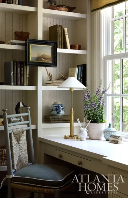 Desk with brass lamp, potted plant, and blue and white vase on shelves.