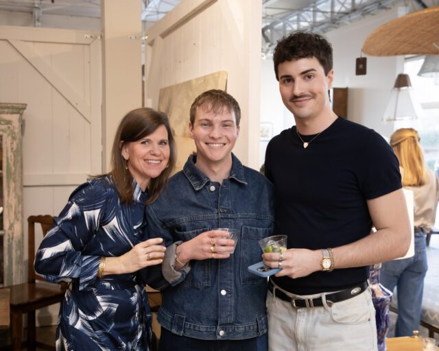 Three people smiling, two men and one woman, holding drinks.