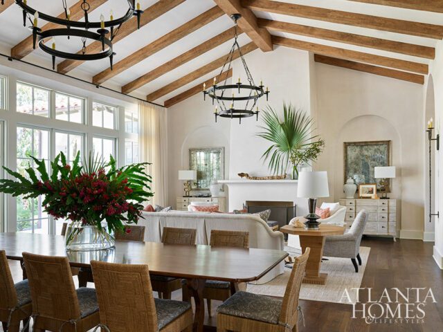 Living and dining room with vaulted beamed ceiling, large windows, fireplace, and floral
