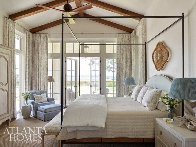 Bedroom with canopy bed, vaulted ceiling, exposed beams, and French doors overlooking the water.