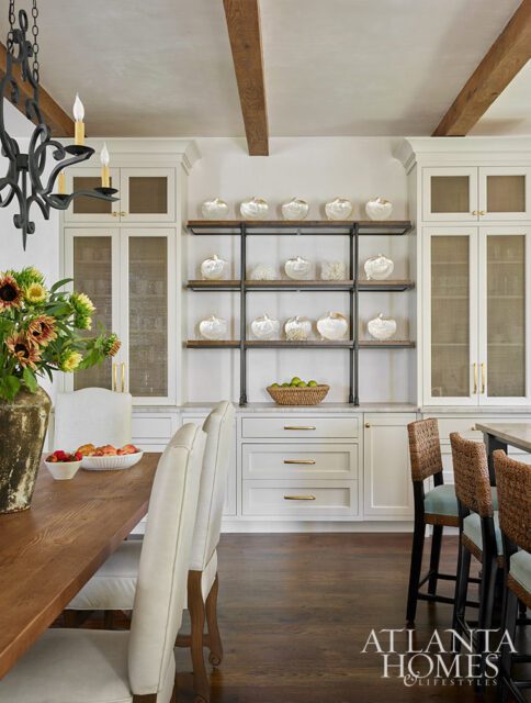 Dining room with white built-in cabinets, open shelves displaying decorative pumpkins, and a wooden