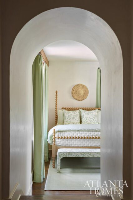 Bedroom with light green leaf-patterned bedding, a wooden bed frame, and a matching bench.