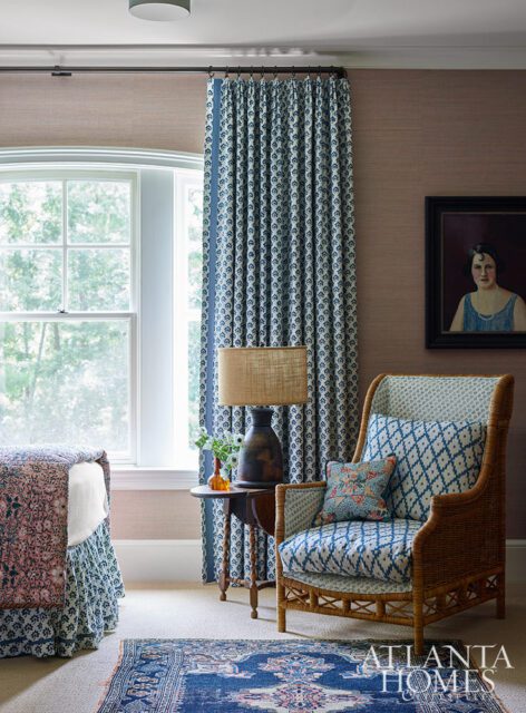 Bedroom with blue and white patterned curtains, a wicker chair with blue cushions, and a vintage