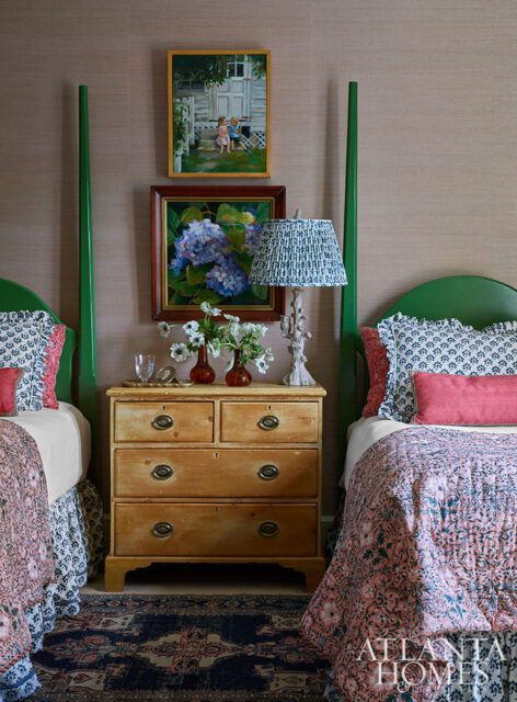 Bedroom with two green four-poster beds, a wooden dresser, and floral paintings.