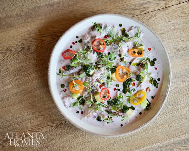 Ceviche with sliced bell peppers, avocado, and microgreens in a creamy sauce
