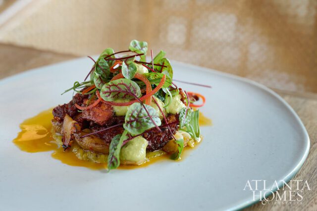 Savory dish with greens, sauce, and meat on a light blue plate.