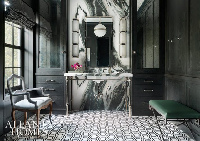 Dark wood paneled bathroom with marble vanity, hexagonal floor tiles, and a green bench.