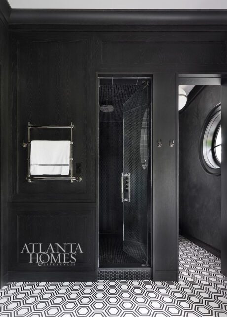Black paneled bathroom with glass shower, hexagonal floor tiles, and towel warmer