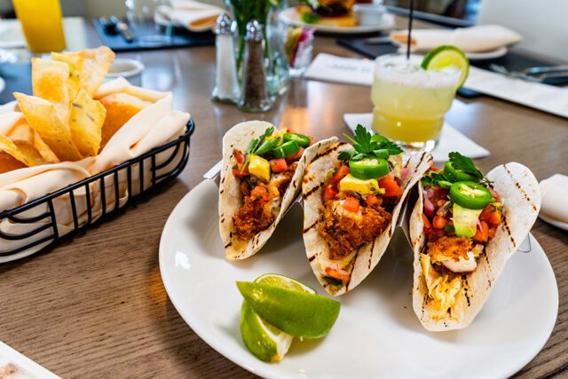 Three fish tacos with pico de gallo, avocado, jalapeños, and cilantro