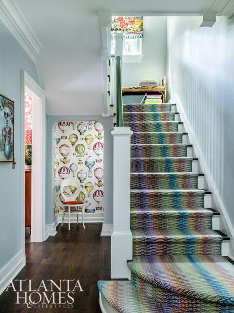 Hallway with hot air balloon wallpaper and a rainbow striped carpet runner on the stairs.