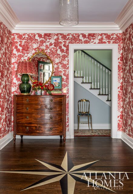 Hallway with red floral wallpaper, antique dresser, and compass rose inlay floor