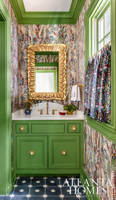 Green vanity with sunburst knobs, marble countertop, and ornate gold mirror.