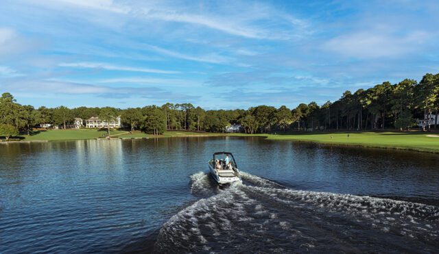 Boat on a lake with a golf course and houses in the background