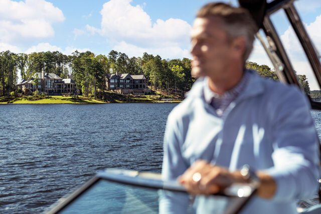 Man on boat with lake and houses in background