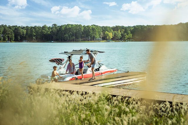Family on a boat docked on a lake with trees in the background