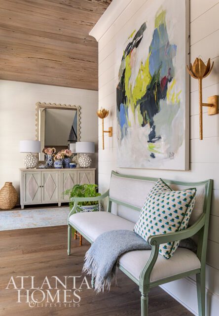 Hallway with abstract art, green bench, and console table with mirror