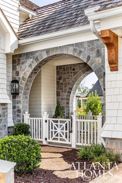 Stone archway with white picket gate and cedar shake roof. Atlanta Homes logo visible.