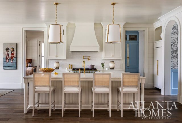 White kitchen with island, cane-backed bar stools, subway tile backsplash, and blue cabinet doors.