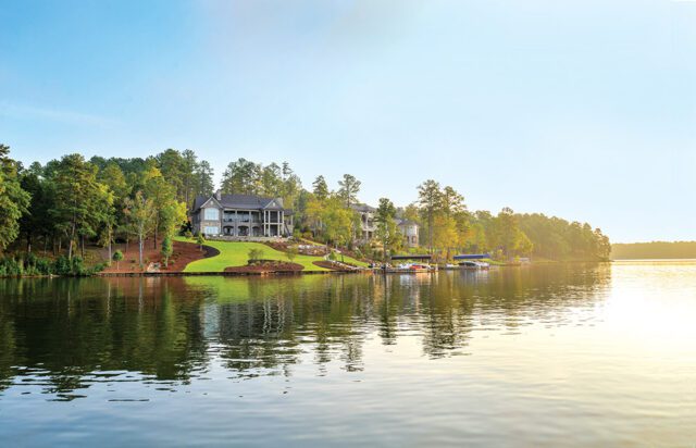 Luxury lake houses with boat docks on a tree-lined shore under a clear sky.