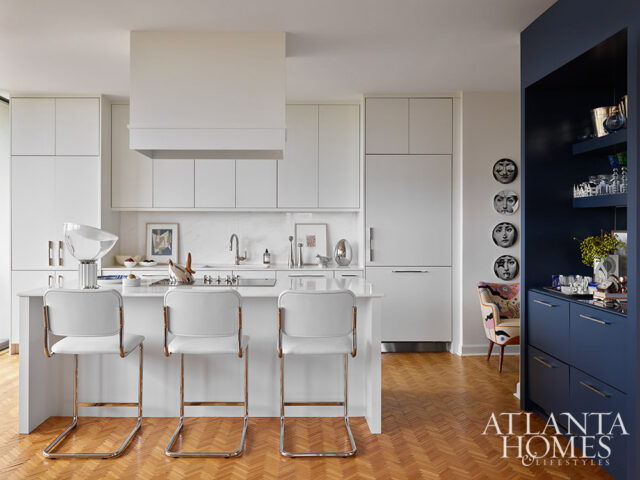 White kitchen with island, bar stools, navy cabinetry, and decorative plates