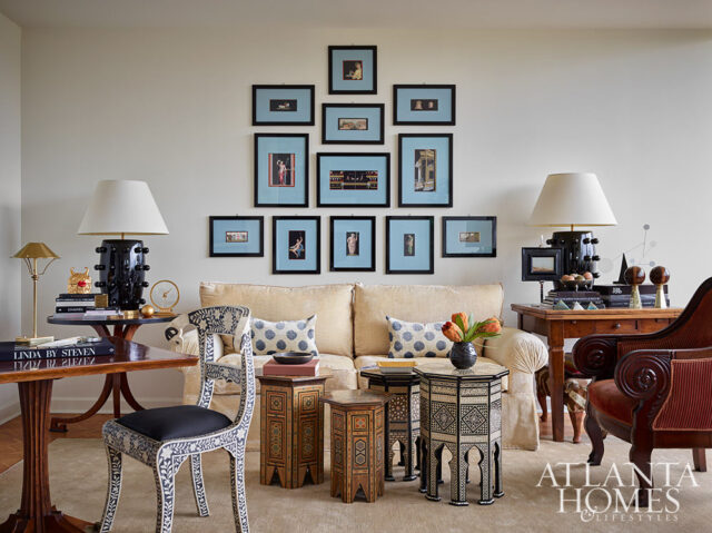 Living room with cream sofa, gallery wall of framed art, patterned chairs, and mosaic accent tables.