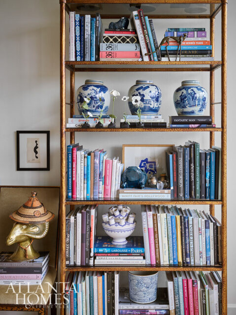Gold metal bookshelf filled with books, blue and white ginger jars, and decorative objects.