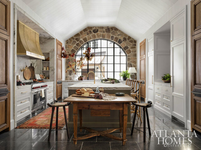 Kitchen with vaulted ceiling, stone arch window, marble island, and wood cabinetry