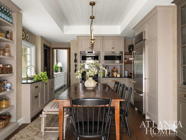 Kitchen with taupe cabinets, wood dining table, black chairs, and built-in appliances.