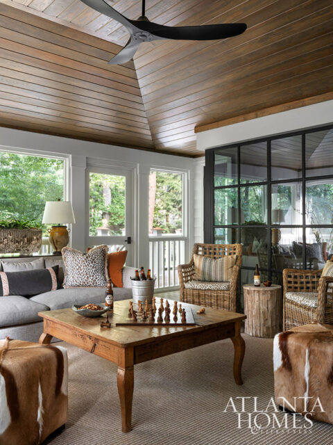 Sunroom with wood-paneled ceiling, gray sectional sofa, wicker chairs, and wooden coffee table with